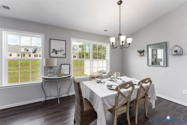 a dining room with wooden floor a chandelier a glass table and chairs