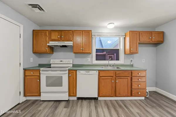 a kitchen with stainless steel appliances granite countertop a sink stove and wooden cabinets