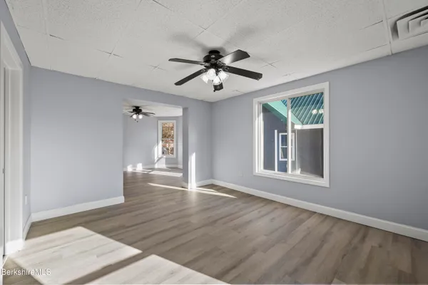 a view of an empty room with a window and wooden floor