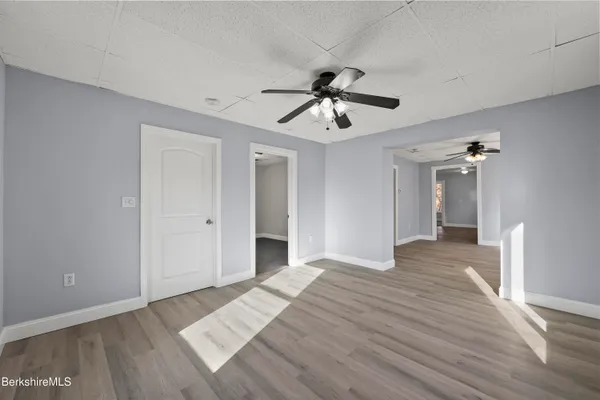 a view of empty room with wooden floor and ceiling fan