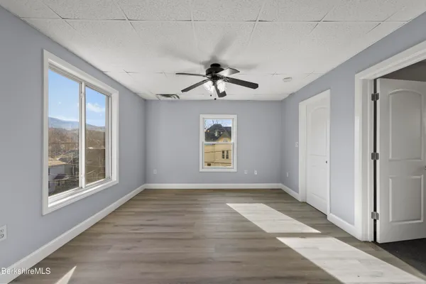 a view of empty room with wooden floor and fan