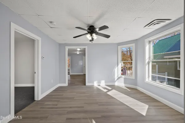 a view of a livingroom with a chandelier fan and windows