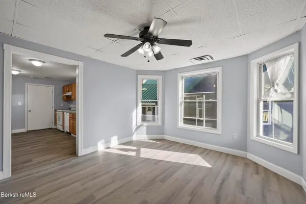 a view of an empty room with wooden floor and a window