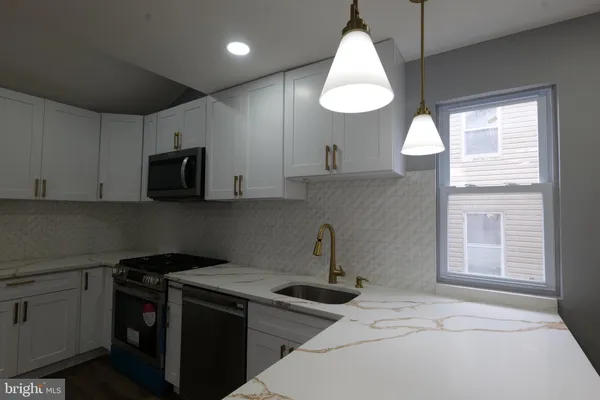a kitchen with stainless steel appliances a stove a sink and a microwave