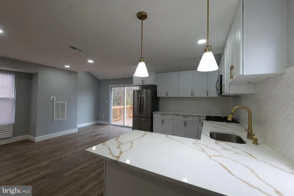a kitchen with a stove a refrigerator a sink and chairs