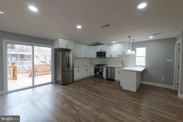 a large kitchen with stainless steel appliances granite countertop a stove a sink dishwasher and a refrigerator with wooden floor