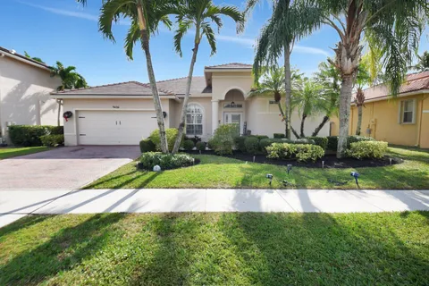 a front view of a house with a yard and palm trees