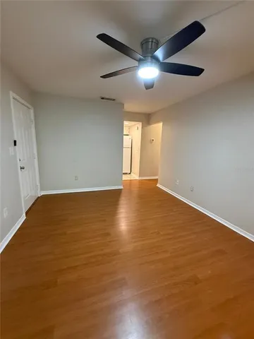 a view of an empty room with a window and wooden floor