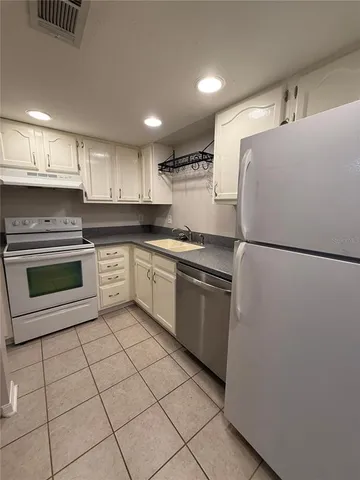 a kitchen with granite countertop white cabinets and appliances