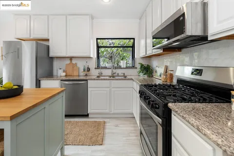 a kitchen with stainless steel appliances granite countertop a sink stove refrigerator and cabinets