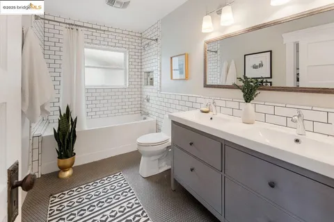 a spacious bathroom with a double vanity sink a mirror and a toilet