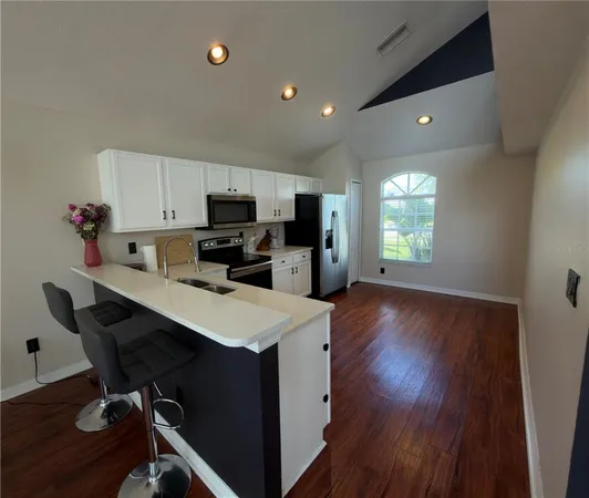 a kitchen with a sink a stove a refrigerator cabinets and wooden floor