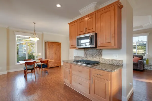 a kitchen with stainless steel appliances granite countertop wooden cabinets a dining table and chairs