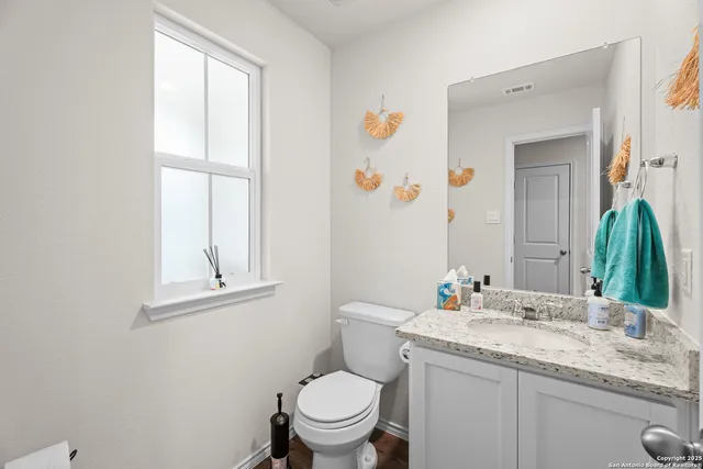 a bathroom with a granite countertop toilet sink and mirror