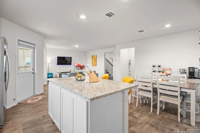 a kitchen with stainless steel appliances granite countertop table chairs and white cabinets
