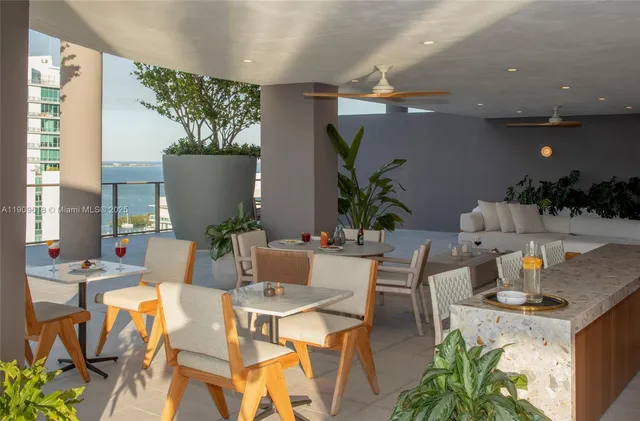 a view of a dining room with furniture a potted plant and a large window
