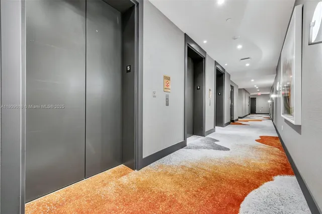 a view of a hallway with wooden floor and a bathroom