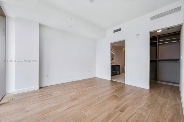 a view of empty room with wooden floor and cabinets