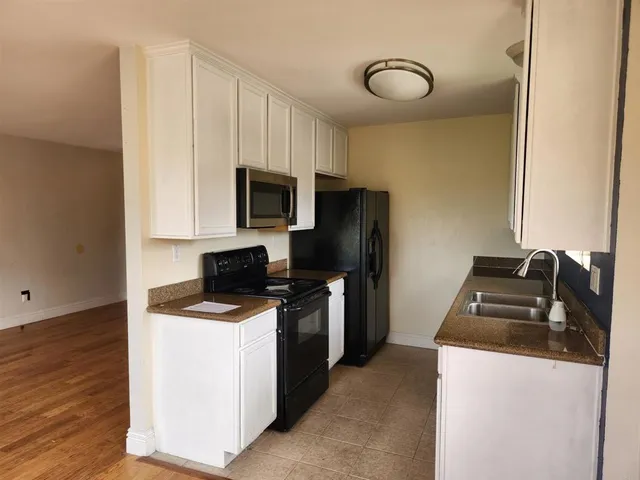a kitchen with a sink stainless steel appliances and wooden floor