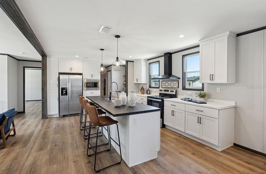 1089 Aspen Street Bunnell, FL 32110 - Photo 8 of 15 a kitchen with stainless steel appliances kitchen island a refrigerator a sink dishwasher a stove and white cabinets with wooden floor