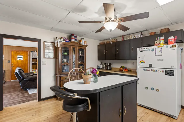 a kitchen with a refrigerator a sink dishwasher a dining table and chairs with wooden floor