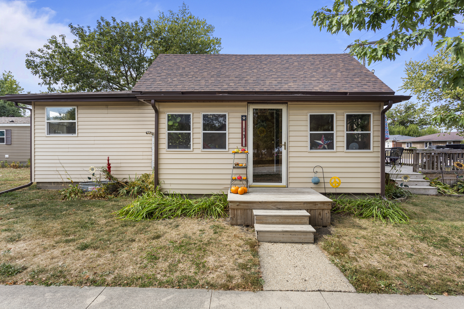 13 Willow Street Dewey, IL 61840 - Photo 2 of 27 a view of a white house with a small yard plants and large tree