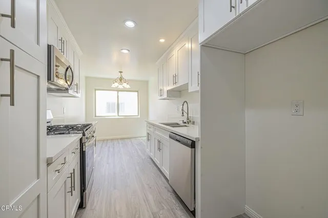 a kitchen with stainless steel appliances granite countertop a stove a sink and a white refrigerator