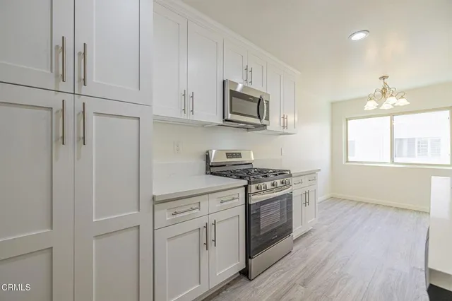 a kitchen with a sink stove top oven and white cabinets