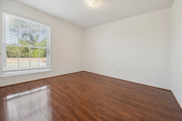 a view of an empty room with wooden floor and a window