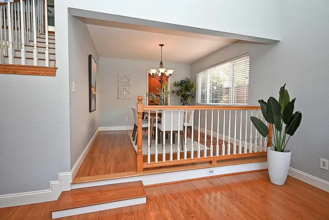 a dining room with furniture potted plants a chandelier and wooden floor