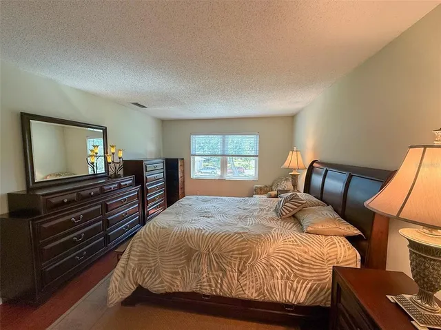 a bedroom with a bed and flat tv screen on the dresser