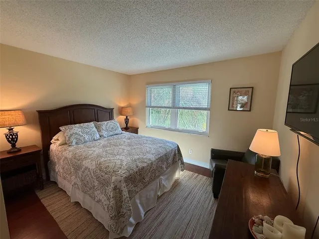 a bedroom with a bed and dresser with wooden floor