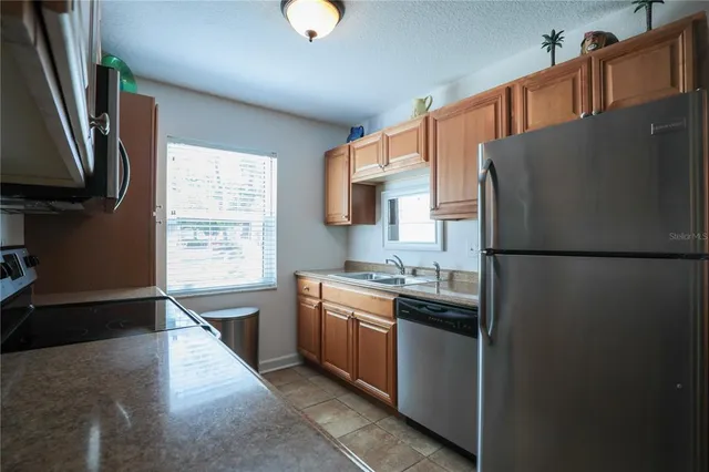 a kitchen with stainless steel appliances granite countertop a refrigerator a stove a sink and a microwave