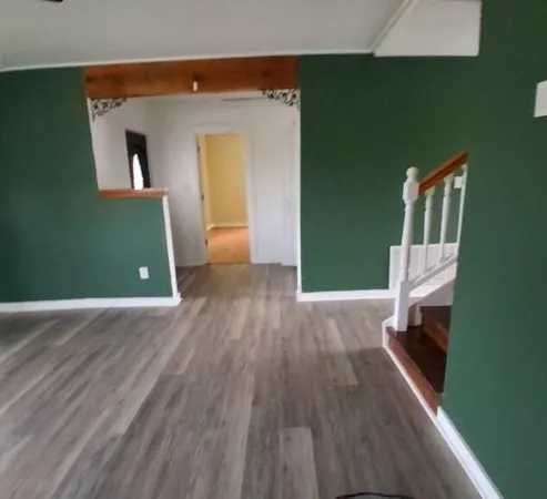 a view of a livingroom with wooden floor and a staircase
