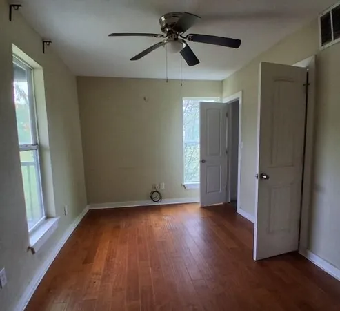 a view of an empty room with wooden floor and a window