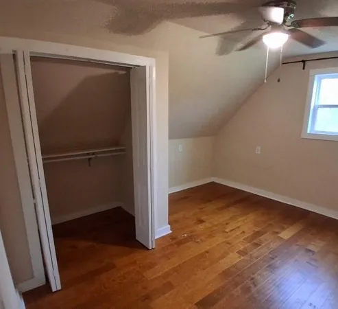 an empty room with wooden floor closet and windows