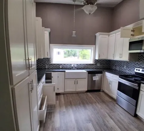 a kitchen with a granite countertop stainless steel appliances a counter top space and cabinets