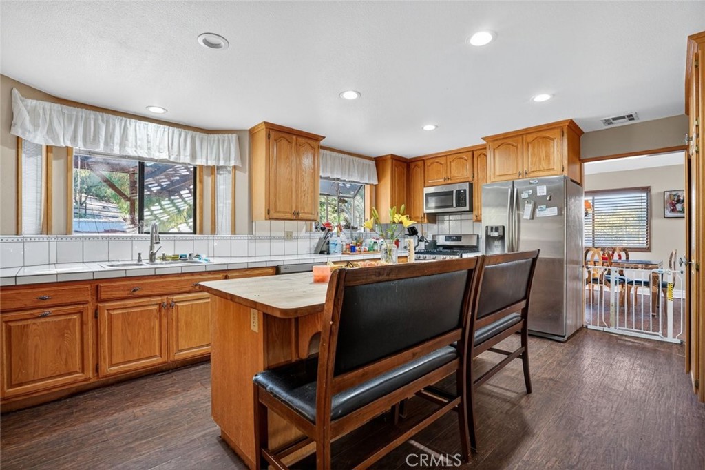 31653 Lake Meadow Road Acton, CA 93510 - Photo 21 of 32 a kitchen with stainless steel appliances granite countertop wooden cabinets a dining table and chairs