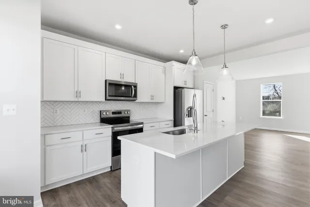 a kitchen with stainless steel appliances granite countertop a refrigerator a sink dishwasher a stove and white cabinets with wooden floor