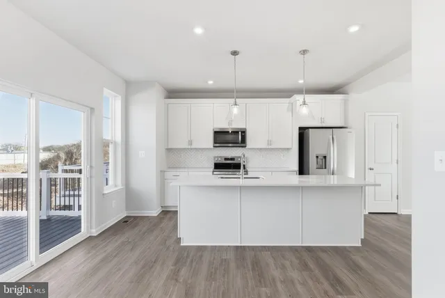 a large kitchen with stainless steel appliances refrigerator a stove top oven and wooden floors