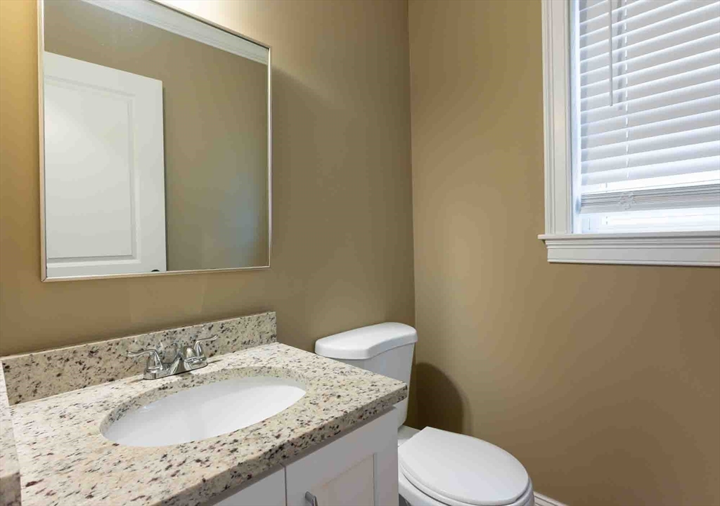 51 Branch Street, Unit 2 Quincy, MA 02169 - Photo 19 of 37 a bathroom with a granite countertop sink toilet and mirror