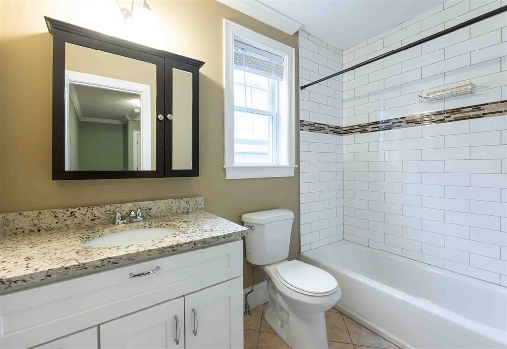 51 Branch Street, Unit 2 Quincy, MA 02169 - Photo 30 of 37 a bathroom with a granite countertop toilet sink and mirror