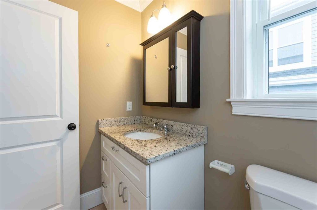 51 Branch Street, Unit 2 Quincy, MA 02169 - Photo 33 of 37 a bathroom with a granite countertop sink and a toilet