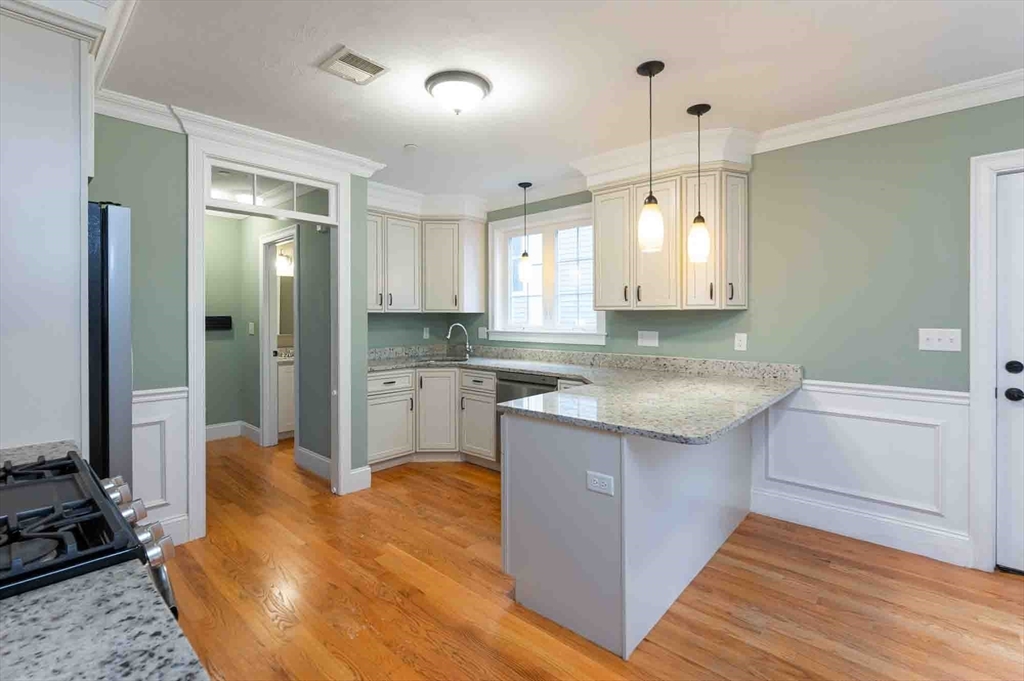 51 Branch Street, Unit 2 Quincy, MA 02169 - Photo 8 of 37 a large kitchen with kitchen island white cabinets and stainless steel appliances