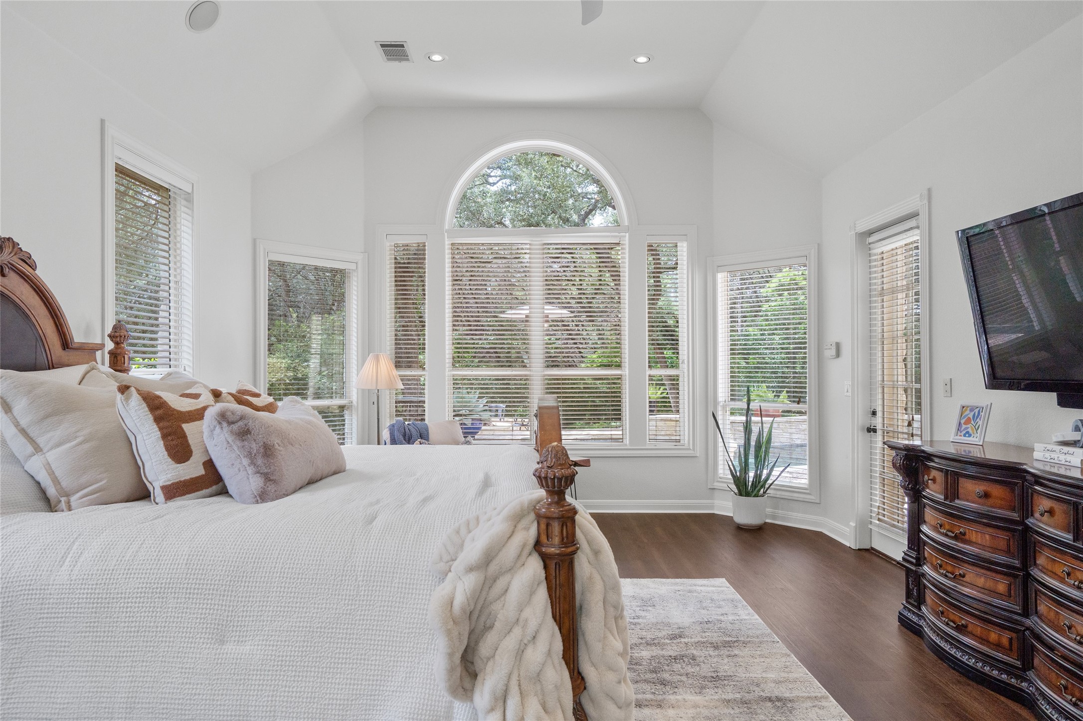 4313 Rio Robles Drive Austin, TX 78746 - Photo 21 of 40 A spacious primary bedroom with soaring vaulted ceilings and abundant natural light from a wall of windows.