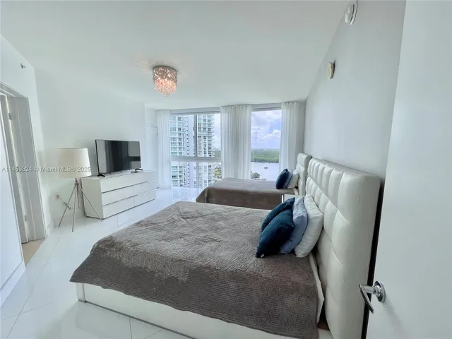 a bedroom with a bed a flat tv screen and a dresser