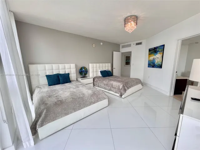 a bedroom with a large bed and a flat tv screen on dresser