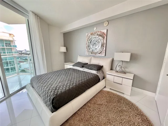 a bedroom with a bed wooden floor and a large window