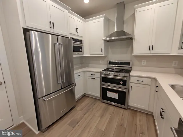 a kitchen with stainless steel appliances a refrigerator a stove and white cabinets