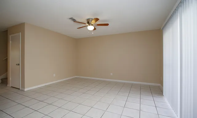 an empty room with windows and fan